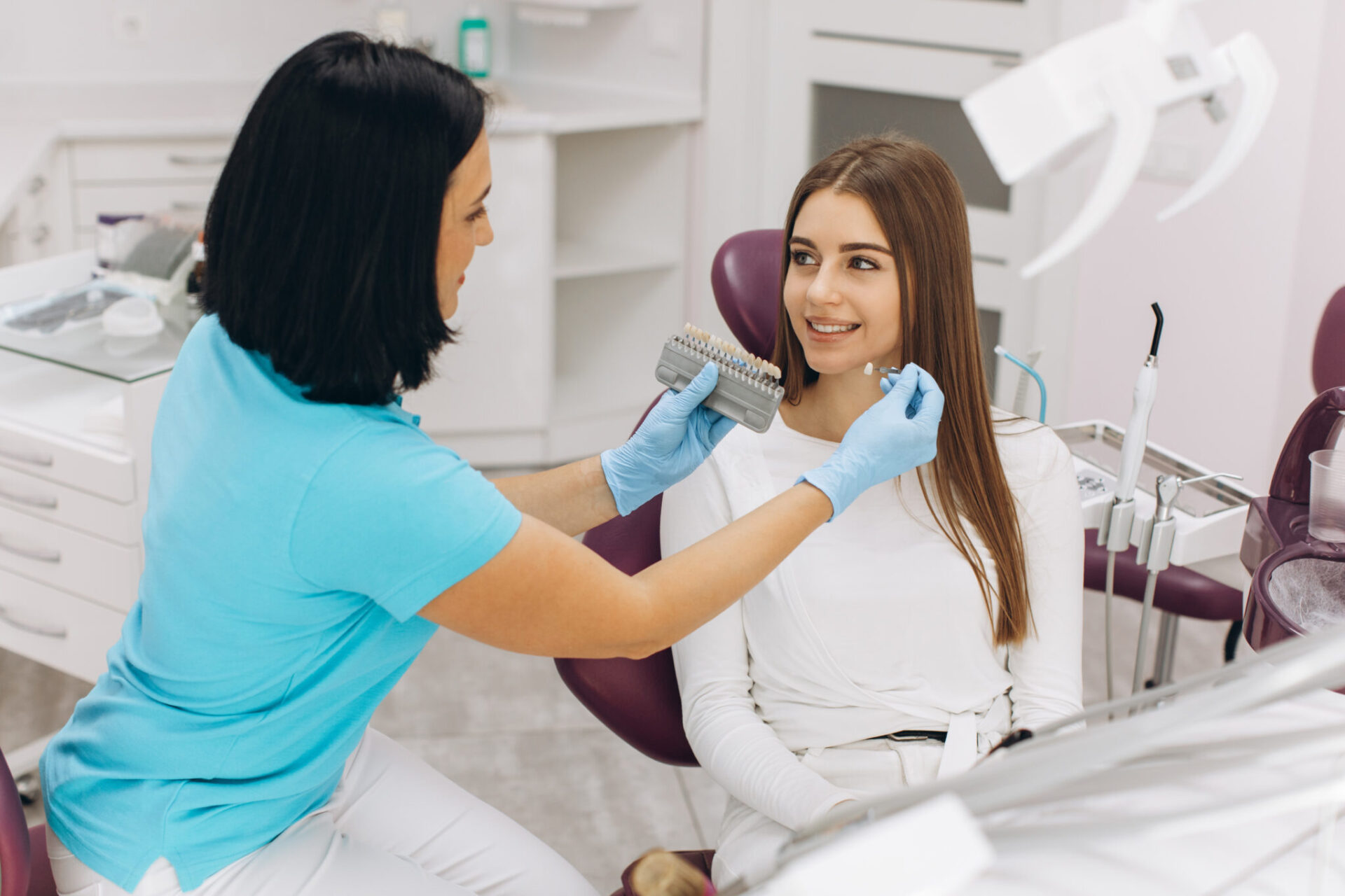 A Female Dentist Helps Her Patient Choose The Color Of The Implant